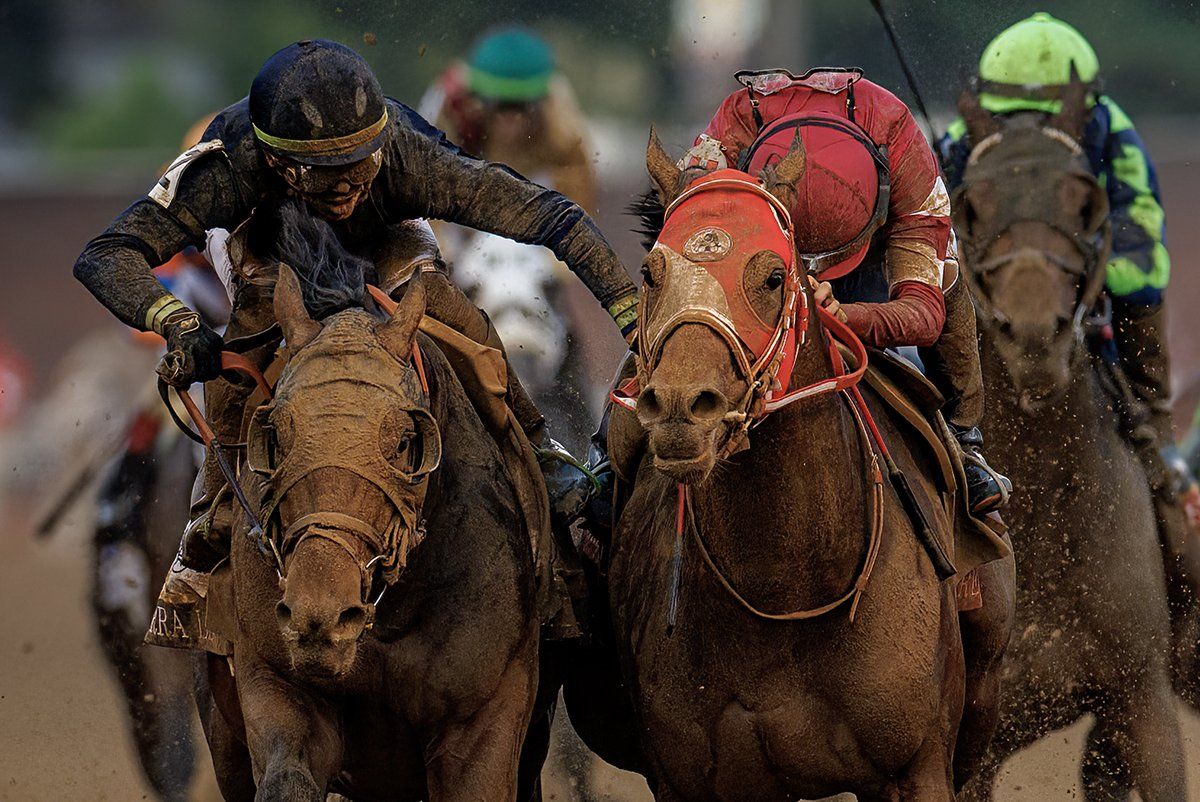 Jockeys and horses covered in mud at the finish
